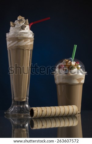 ice coffee in glass and plastic takeaway cup, decorated with whipping cream and bon-bons, advertisement for menu card
