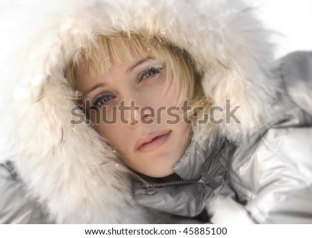 face of a blond girl in white fur and silver coat