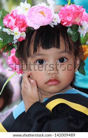 The girl the graduate of school with the flowers on head.