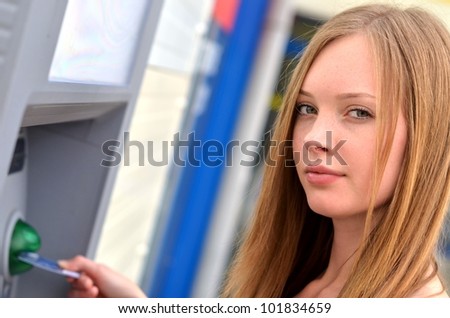 The girl draws out money in a cash ATM