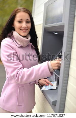 The girl draws out money in a cash ATM
