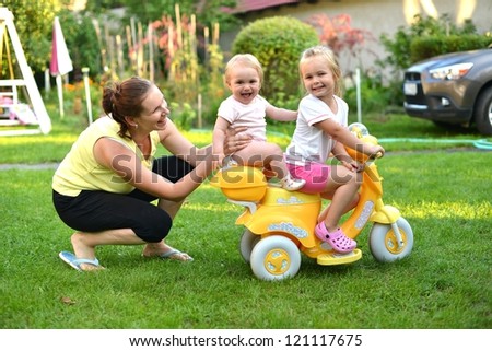 baby with sister rides a toy motorbike and he really enjoys it