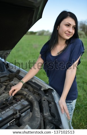 portrait of young beautiful woman with broken car aside