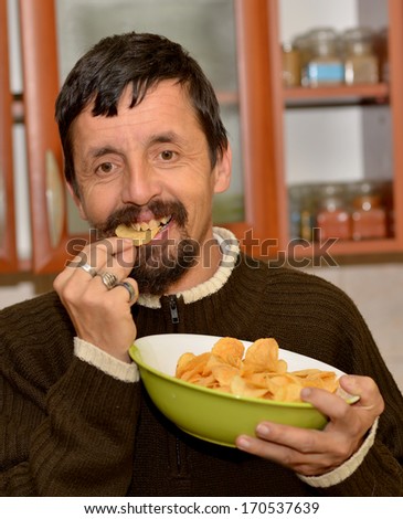 Portrait of young brunette man eating chips