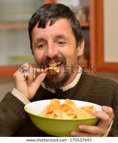 Portrait of young brunette man eating chips