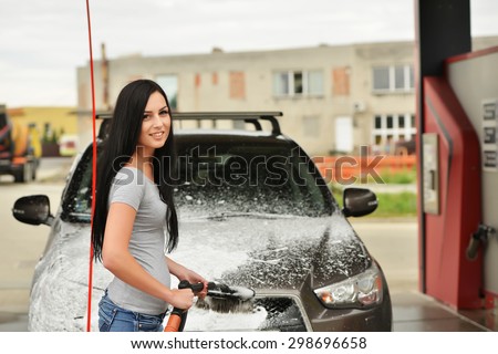 Washing your car. Attractive young woman washing car
