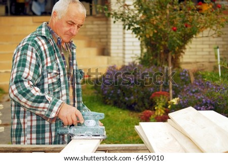 A man working building a home and sanding some wood