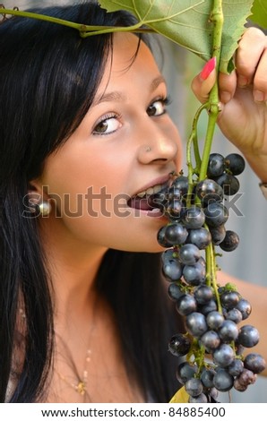 Beautiful woman with perfect hair and skin eating grapes.