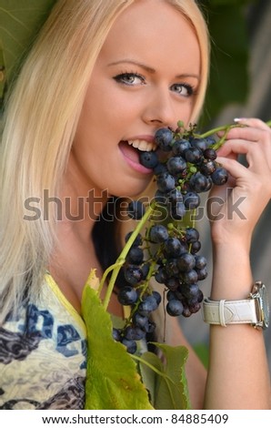 Beautiful woman with perfect hair and skin eating grapes.