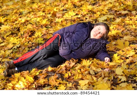 down syndrome woman lying in a pile of leaves.