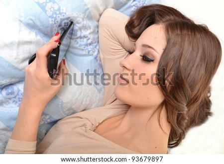 attractive young woman talking on the phone while lying in the bed.