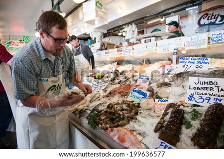 SEATTLE - MAY 10: An employee of City Fish Co. arranges shrimp at Pike Place Market in Seattle on May 10, 2014. Opened in 1917, City FIsh Co. is one of the longest-running fish markets.