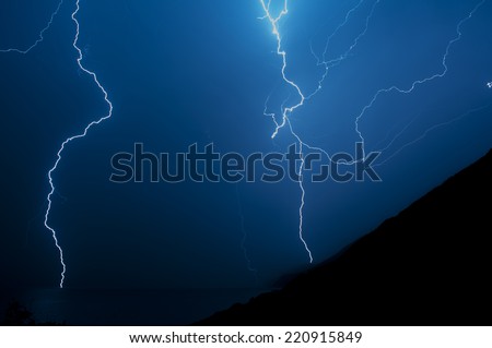 Lightning behind the hill and over the sea.