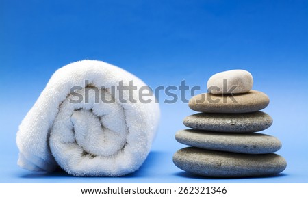 Spa still life,towel and balanced pebbles on blue background.