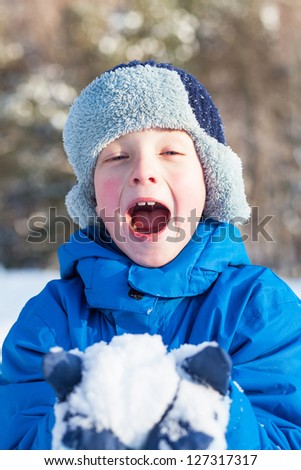 A happy boy is playing with snow on winter