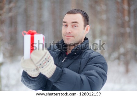 portrait of young man giving a gift in nature