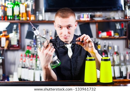 Young  professional barman in action making cocktail drinks