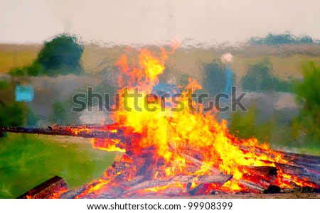 Large bonfire burning with large logs on the background of the beach