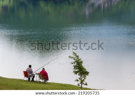 Fishing. Man and woman sitting on the shore of the lake and enjoy fishing