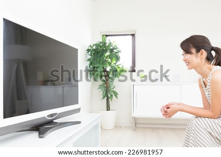 young attractive asian woman watching TV in living room
