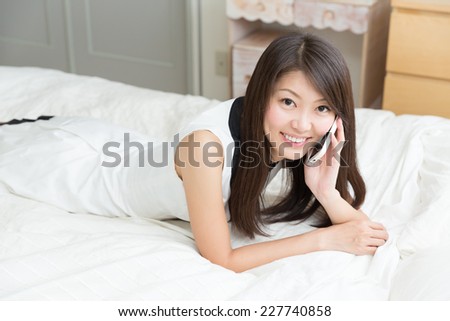 Beautiful young asian woman who talks on the telephone in bed