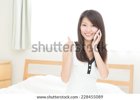 Beautiful young asian woman who talks on the telephone in bed