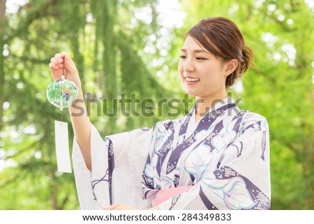 young attractive Japanese woman in a Yukata having a wind bell