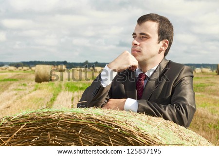 A business man in a suit is based on the stack of hay