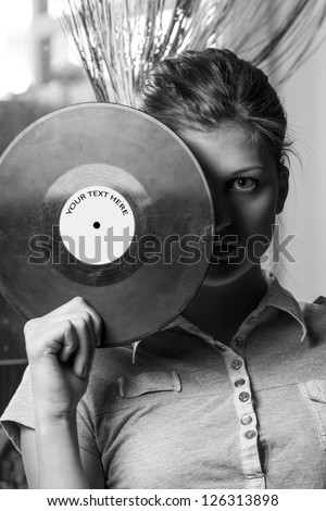 Girl covers her face with a vinyl disc. Gray-scale.