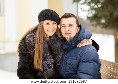 Lovers kissing on the bench in winter park