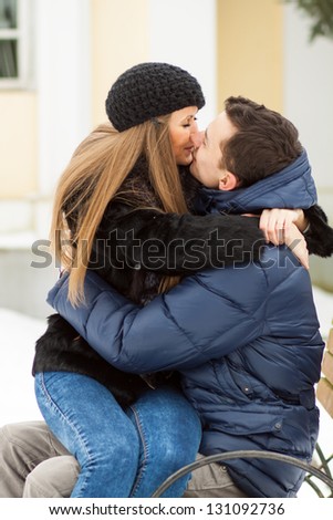Lovers kissing on the bench in winter park