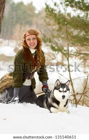 Happy young woman sitting with siberian husky dog in winter forest