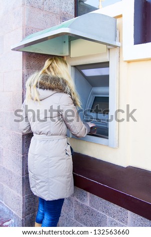 Young Woman using Bank ATM cash machine on the street