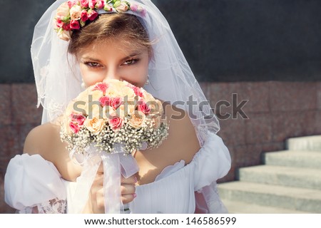 Beautiful young bride hides his face behind a bouquet