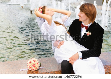 Bride and groom sitting together on the fountain