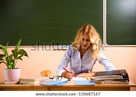 Young pretty teacher checking the tests. Back to school concept.