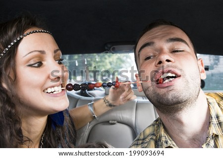 Young couple eating berries in the car