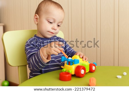 little boy repairs auto sitting at the table