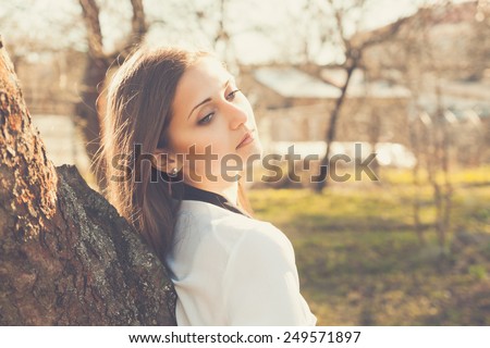Beautiful girl in autumn forest standing near by tree