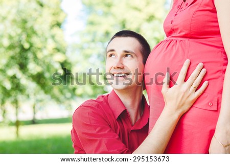 Portrait of father with cheek close to pregnant belly of wife. Pregnant couple. Happy pregnancy.
