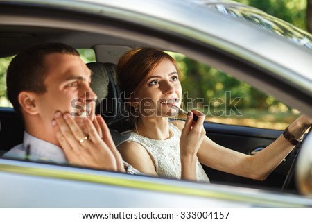 Husband screams until his wife applying lipstick using the rear view mirror in the moving car.