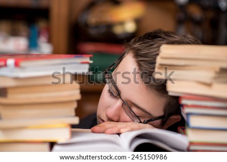 Tired child sleeping while studying. Boy with glasses studying asleep.