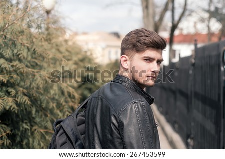 Portrait of a young brutal man with hipster hairstyles wearing leather jacket. Close-up, toned photo