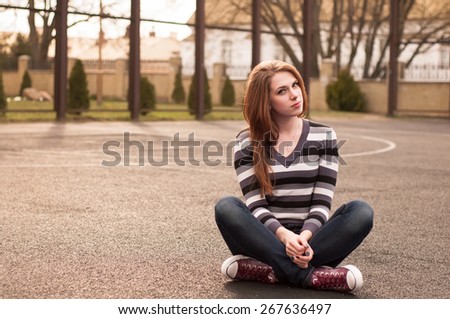 Young pretty woman sitting on the basketball court
