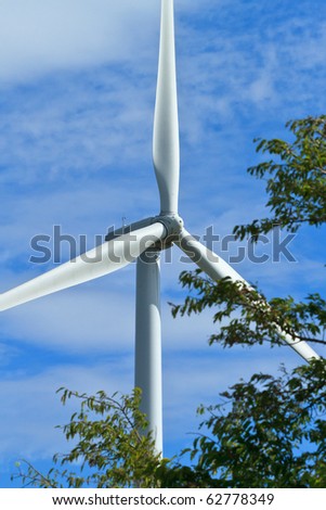 close up pof wind generator\'s propellers tree in the forground