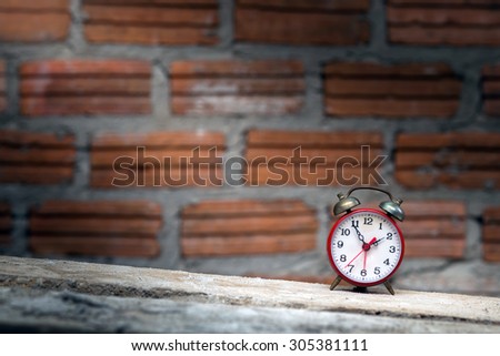 Old red alarm clock and brick wall.