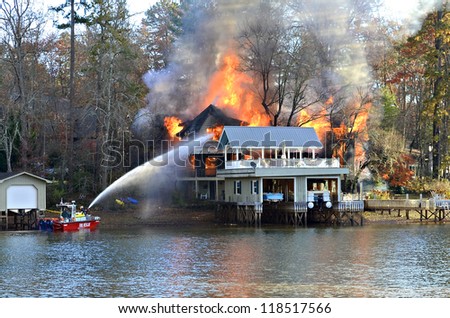 TIGER, GA, USA - NOV. 9: A fire boat on the water sprays a large house fire on November 9, 2012 on Lake Burton in Tiger, Georgia.