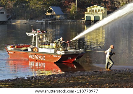 TIGER, GA, USA - NOV. 9: A group of men in a fire boat fighting an evening house fire. November 9, 2012, on Lake Burton.