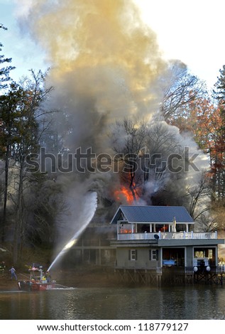 TIGER, GA, USA - NOV. 9: A fire boat on the water spraying a large house, November 9, 2012, on Lake Burton.