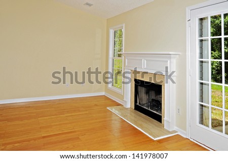 Wood burning fireplace in a room with oak floors flanked by a window and a french door.